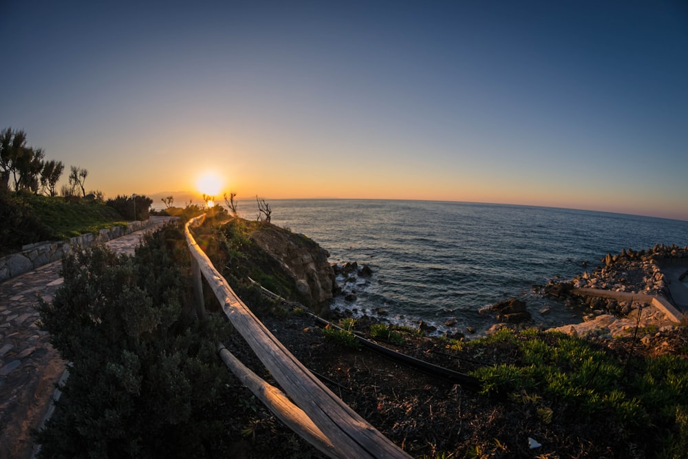 brown wooden bridge across body of water during sunset