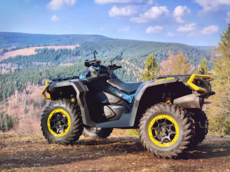 yellow and black atv on brown field under blue sky during daytime