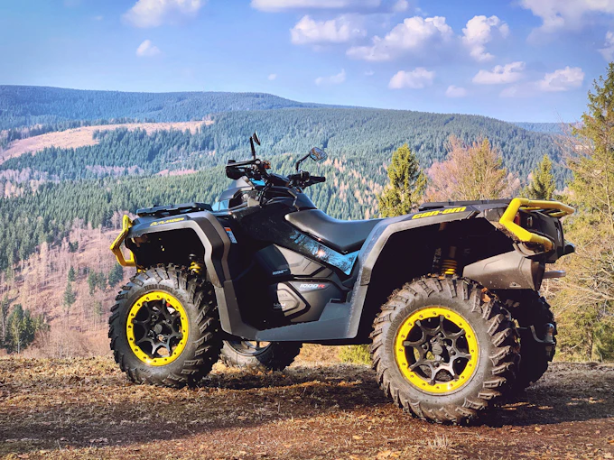A clean black and yellow quad bike standing on dry ground under a blue sky.