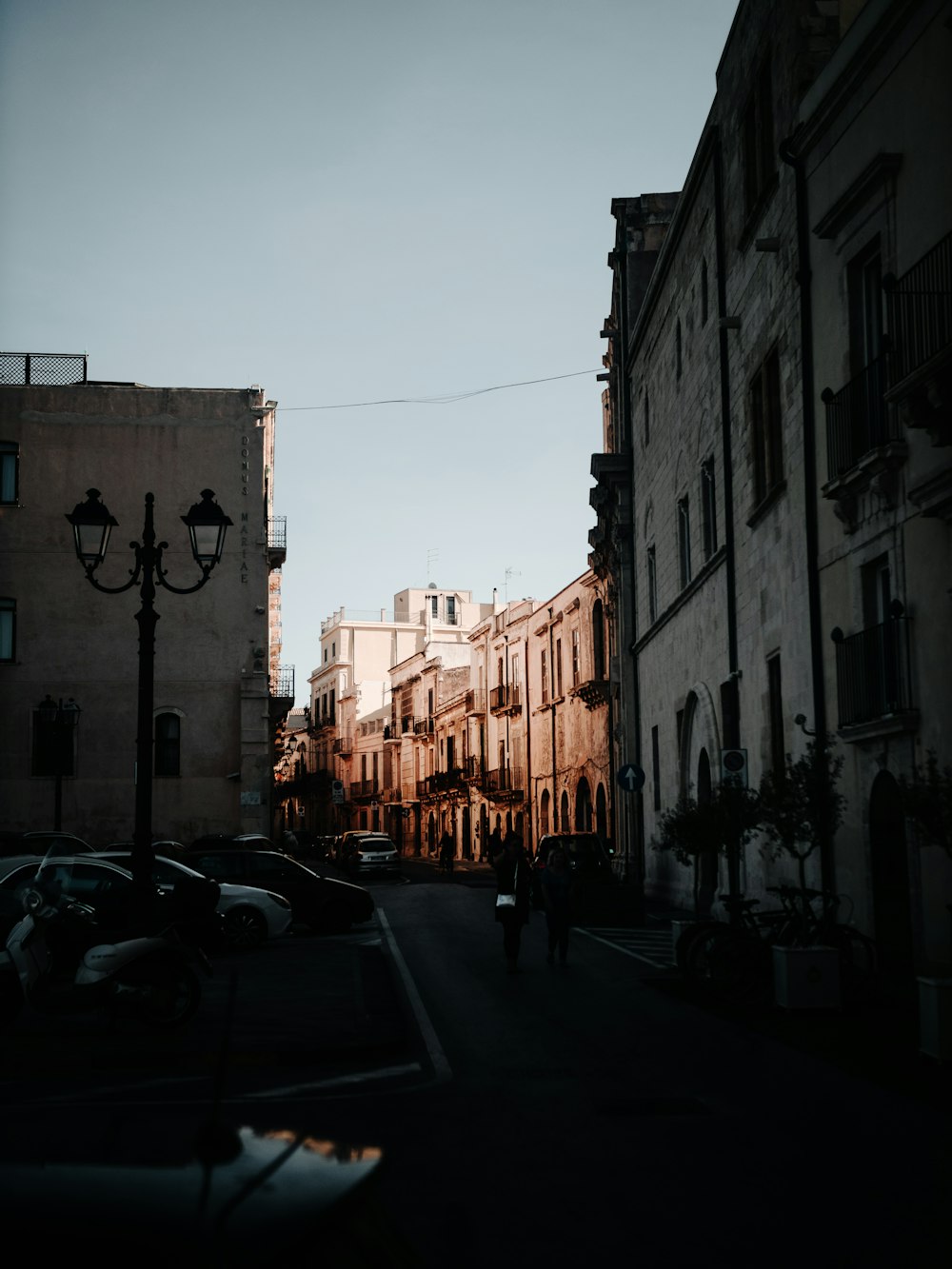 cars parked on side of the road in between buildings during daytime