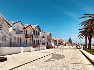 A row of charming villas with colorful gardens and inviting porches under a clear blue sky.