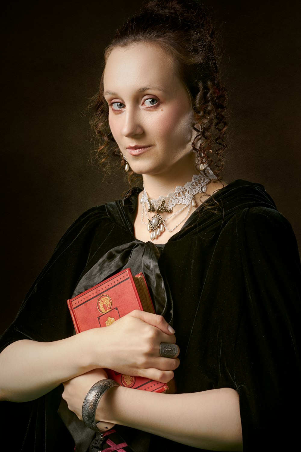 woman in black dress holding red book
