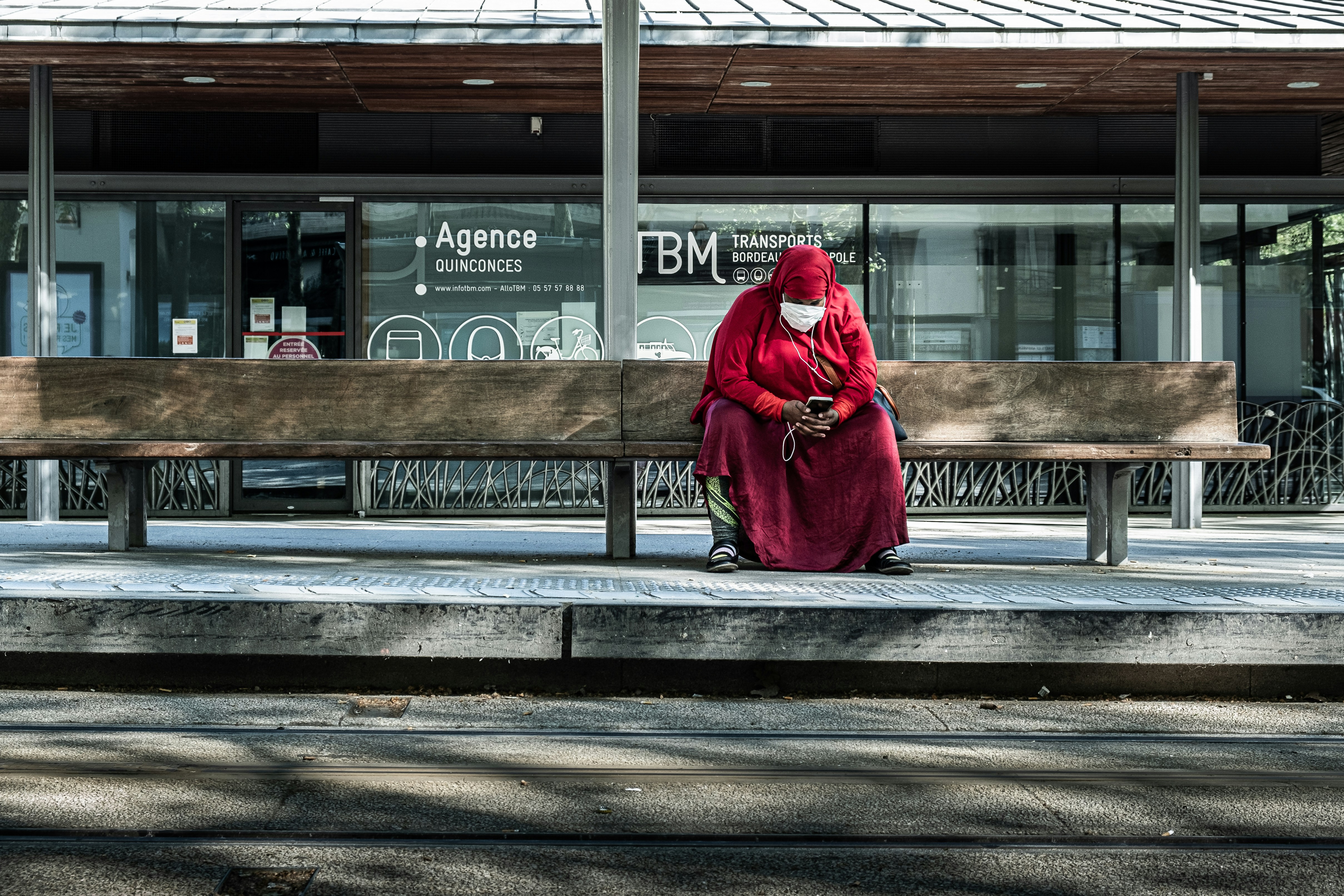 woman in red coat sitting on bench