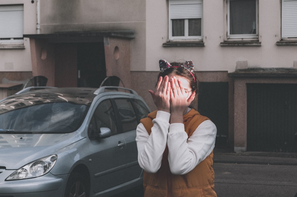 woman in white jacket covering her face with her hands