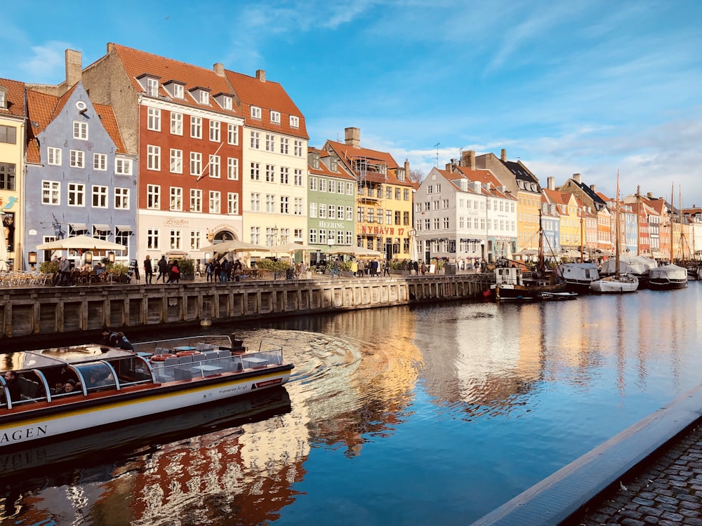 white and brown boat on river near buildings during daytime