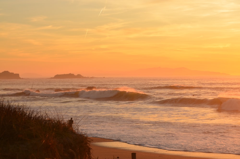 ocean waves crashing on shore during sunset