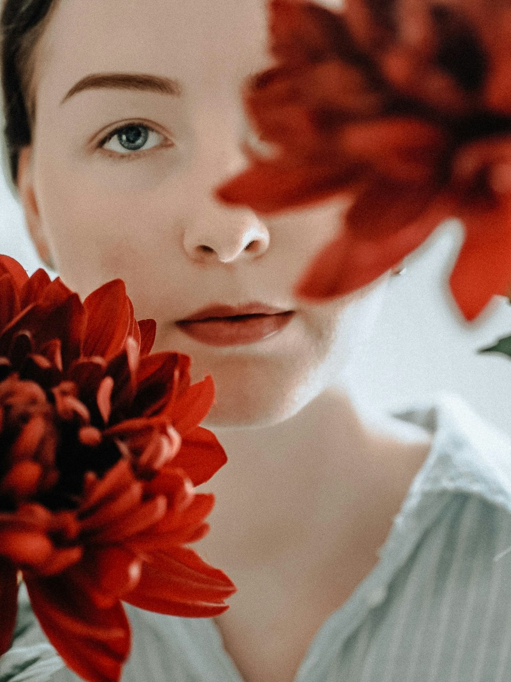 woman in white shirt holding red flower