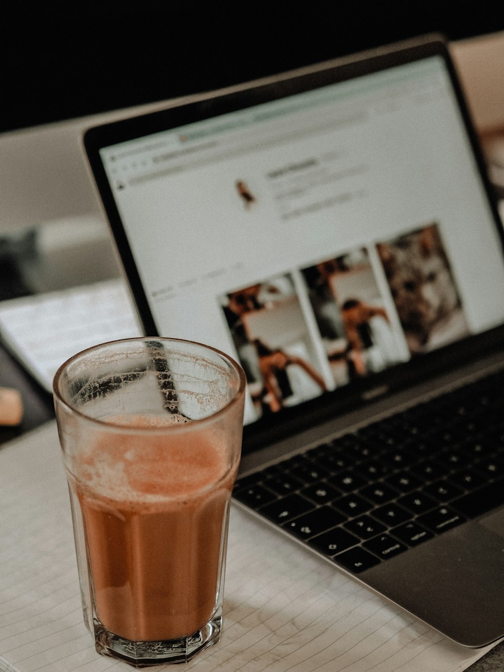 clear drinking glass with brown liquid on macbook pro