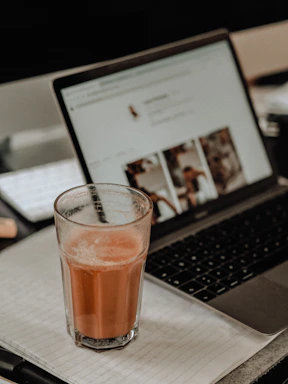 A clean, modern office desk with a laptop, notepad, and a glass of juice, reflecting a professional wholesale soft drinks supplier.