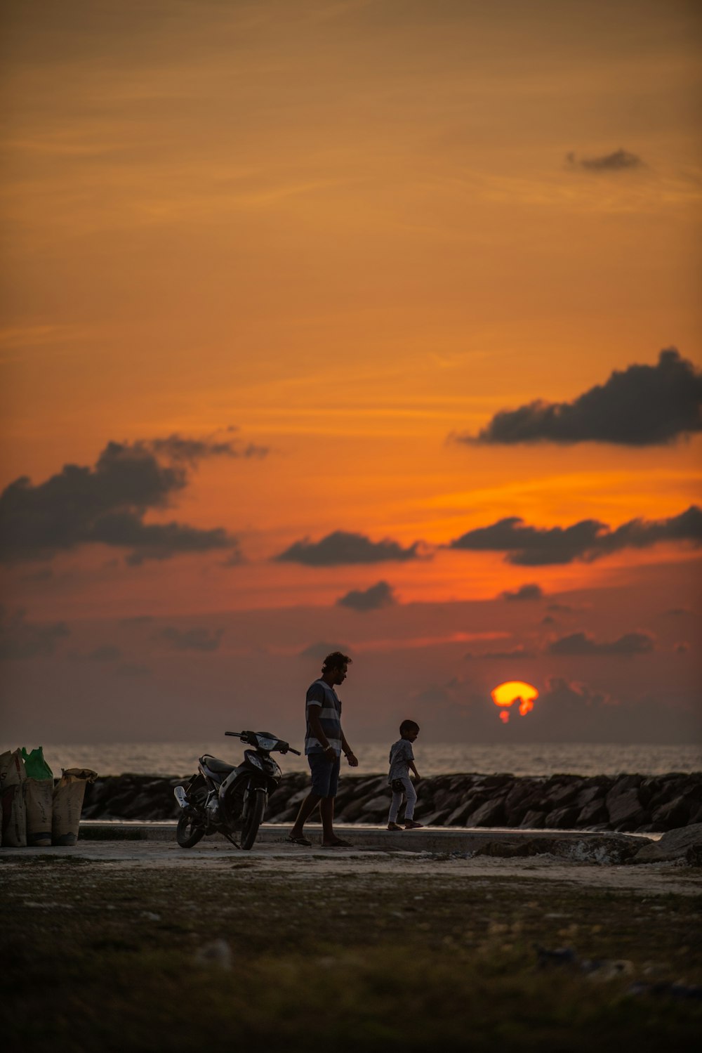 silhouette of 2 person sitting on rock during sunset