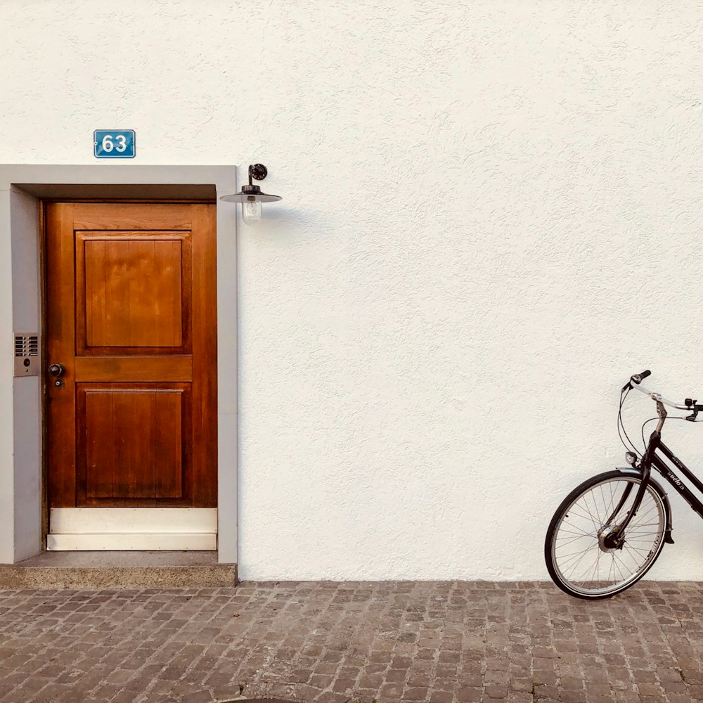 black bicycle leaning on white wall