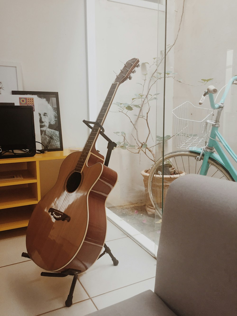 brown acoustic guitar on black steel stand