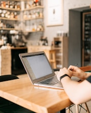 A happy traveler using a laptop to book a car rental online in a cozy cafe.