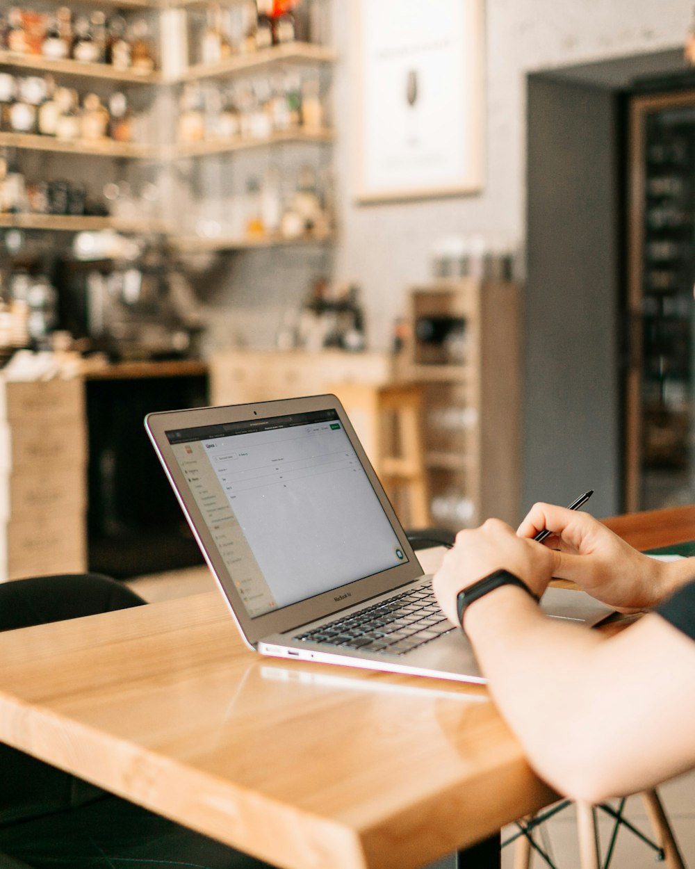 茶色の木製のテーブルでMacBook Airを使っている人