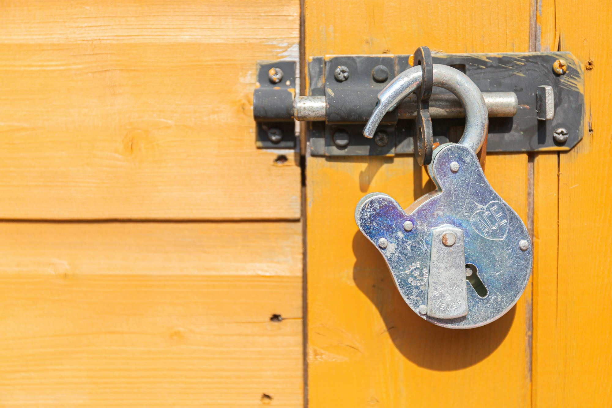 An old fashioned padlock is unlocked, resting on a hatch door