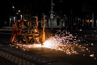 man in orange shirt riding on yellow heavy equipment during night time