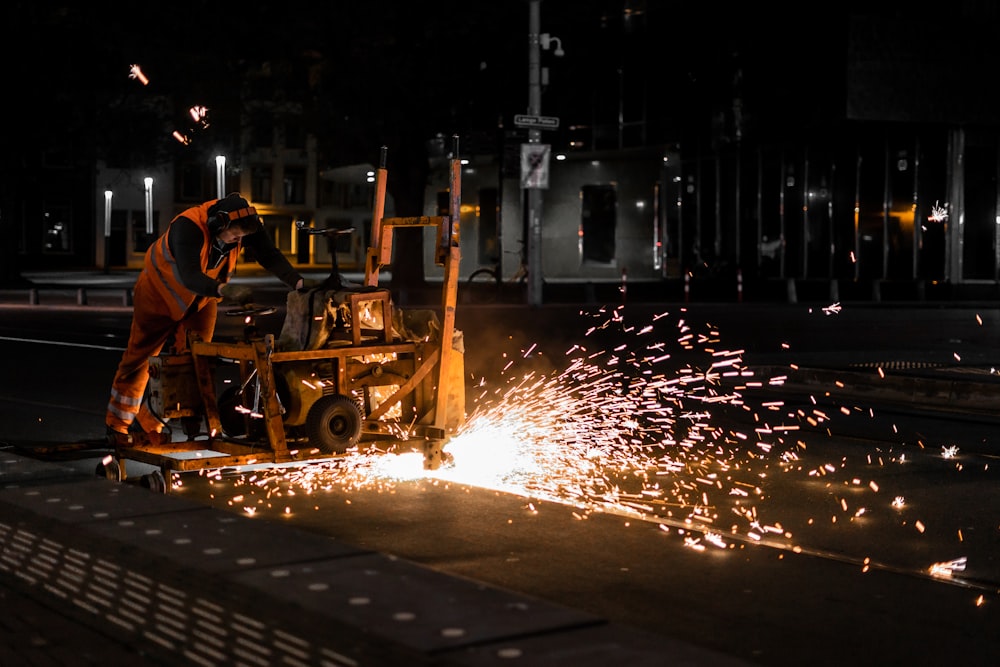 man in orange shirt riding on yellow heavy equipment during night time