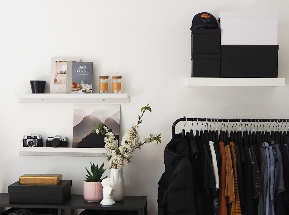 a black and white closet with clothes and a vase of flowers