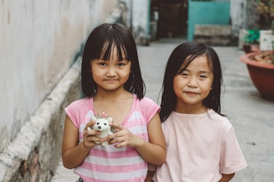 girl in pink and white stripe crew neck t-shirt holding white puppy