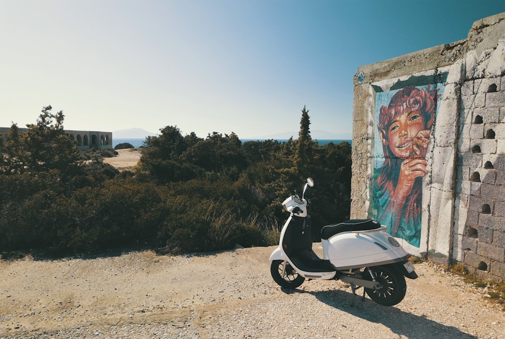 scooter noir et blanc garé à côté d’un mur brun