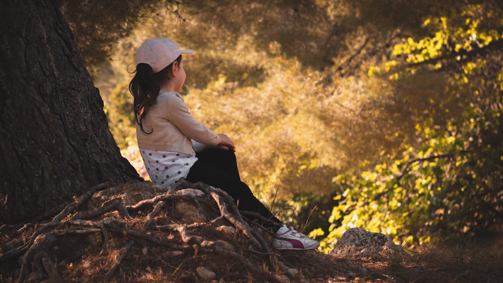 woman in white shirt and black pants sitting on brown tree log during daytime