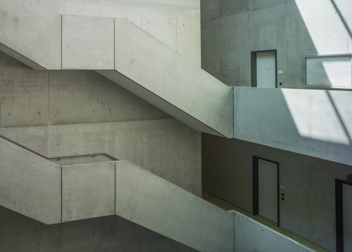 Escalera de concreto blanco junto a una puerta de madera negra