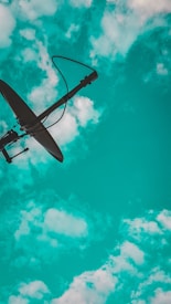 A satellite dish is silhouetted against a vibrant turquoise sky with scattered white clouds.
