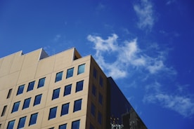 Professional appraiser measuring a building exterior under a clear blue sky