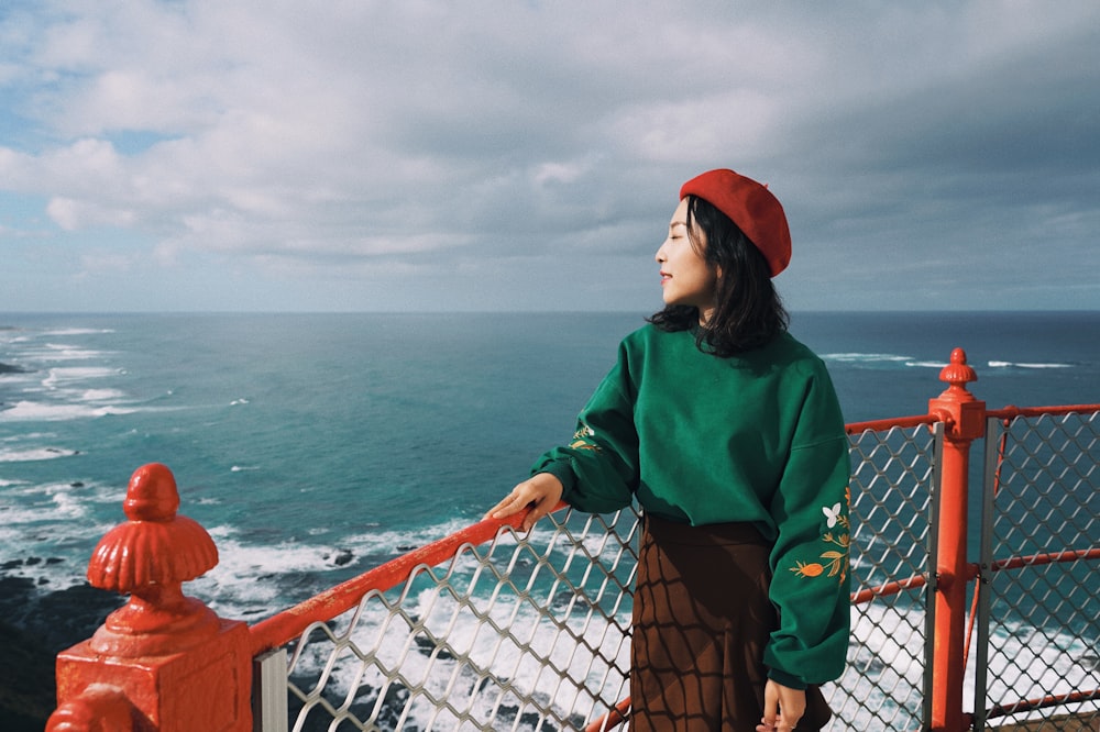 woman in green hoodie standing on dock during daytime