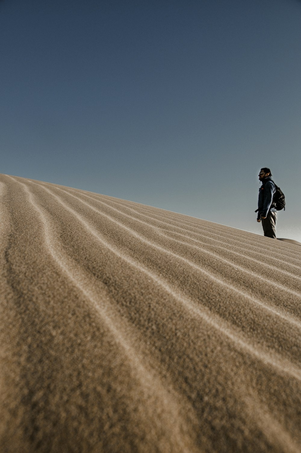 a man standing on top of a sandy hill