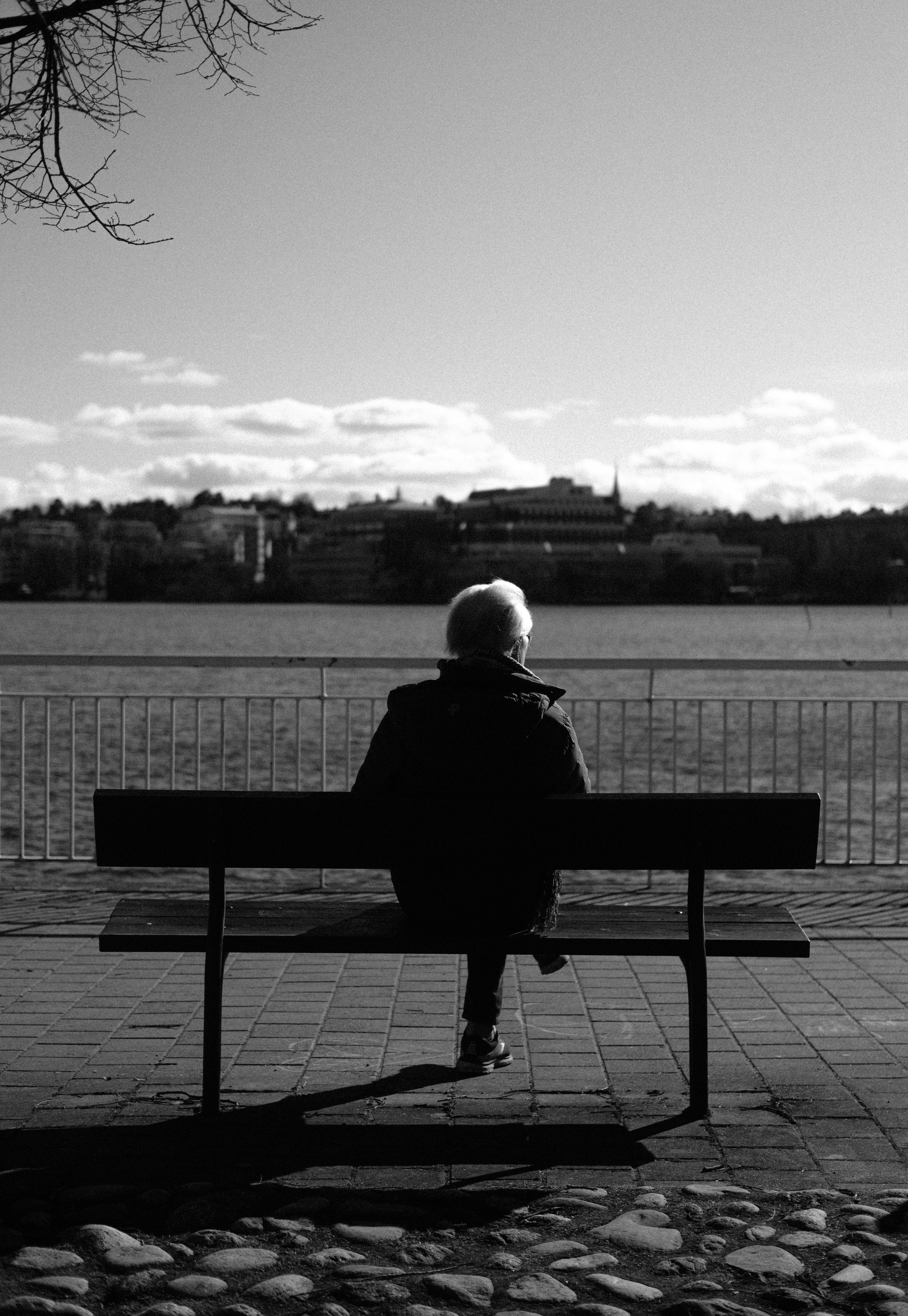 grayscale photo of person sitting on bench