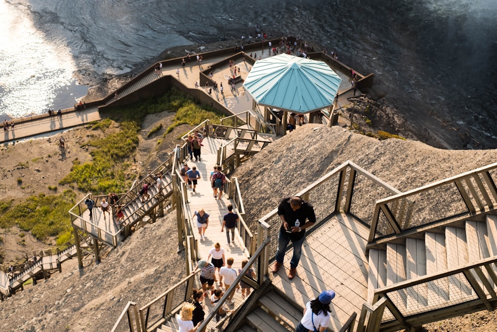 people walking on wooden stairs near body of water during daytime