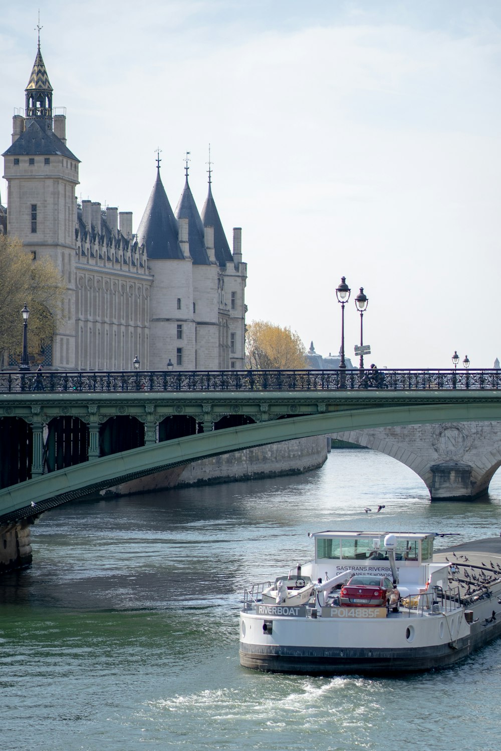 weißes und rotes Boot tagsüber auf dem Fluss in der Nähe der Brücke