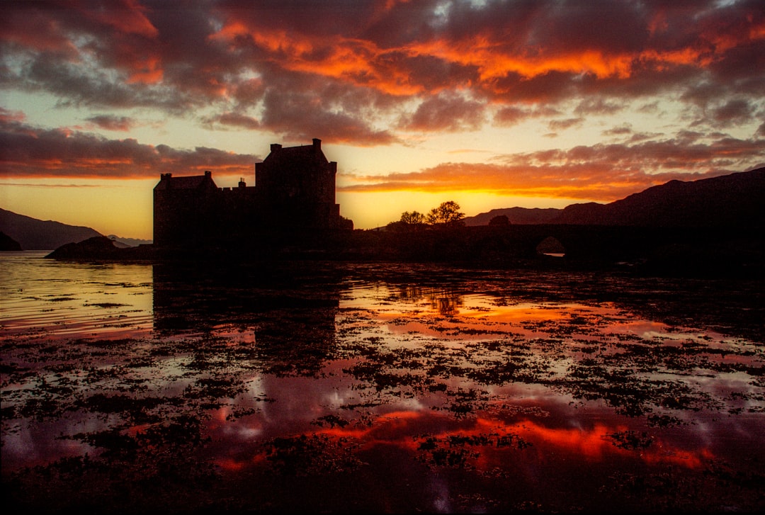 silhouette of building near body of water during sunset