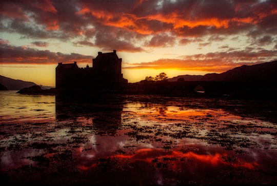silhouette of building near body of water during sunset in Eilean Donan United Kingdom