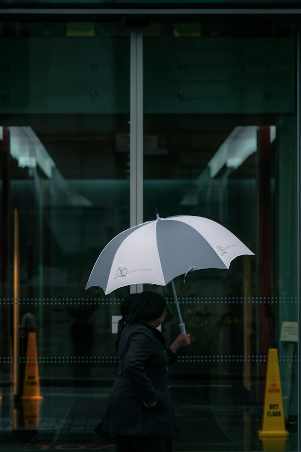 建物の前で銀色の傘をさす人物のシルエット