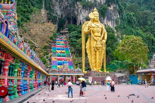 people walking on street near gold statue during daytime in Batu Caves Malaysia