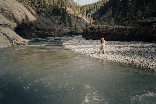 man in black shorts standing on rocky shore during daytime in Crescent Falls Canada