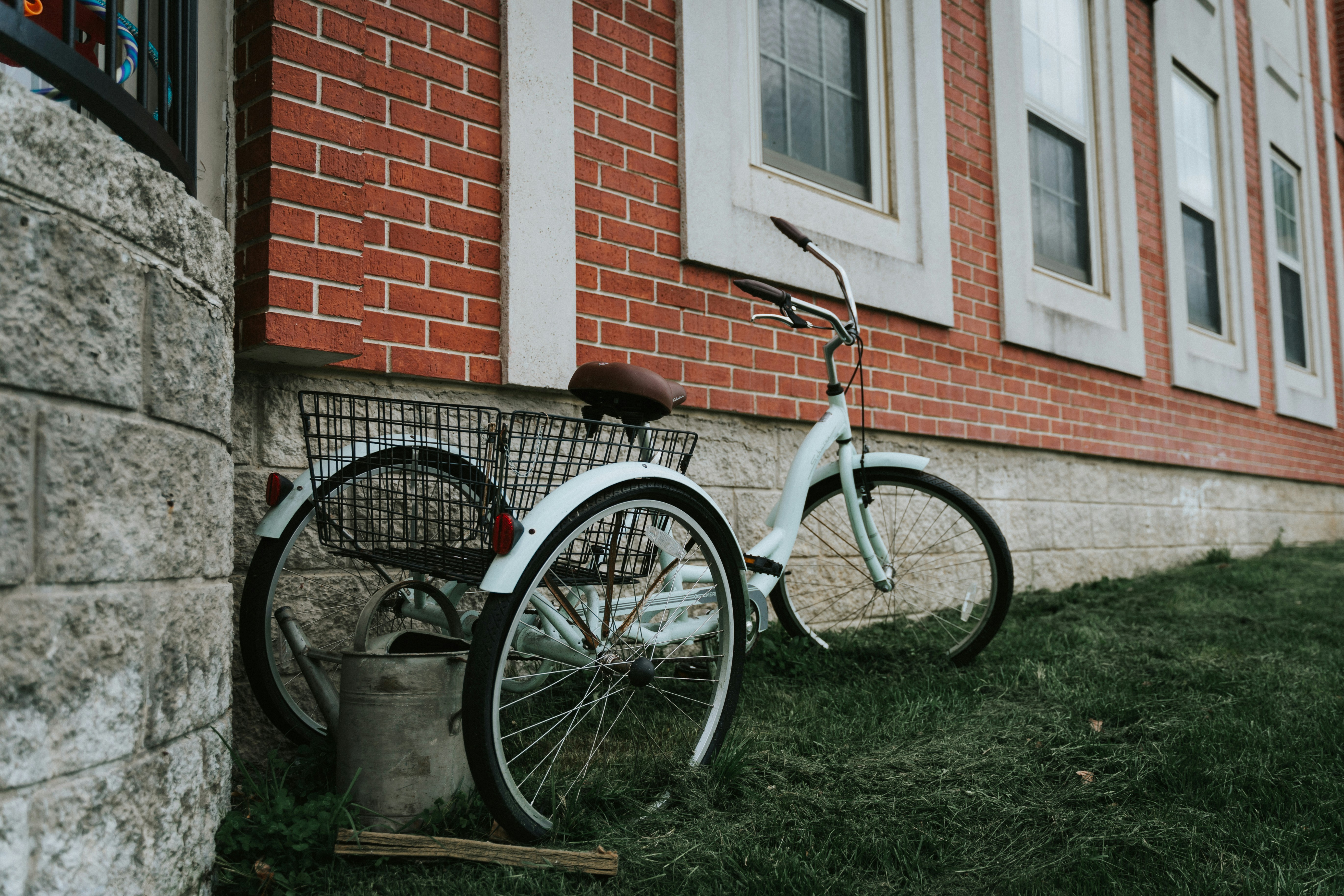black and white city bike parked beside brown brick wall