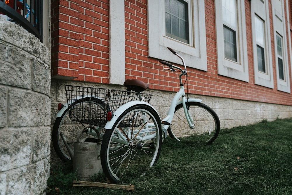 black and white city bike parked beside brown brick wall