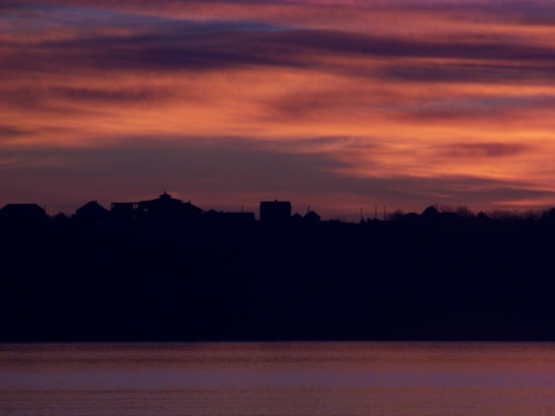 A peaceful sunset over a quiet village, evoking a sense of fulfillment and calm.