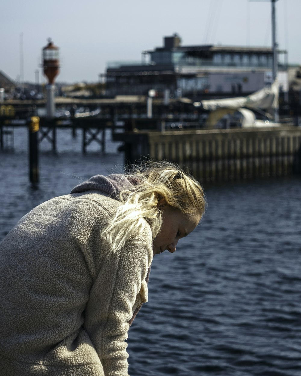 woman in beige sweater standing on dock during daytime
