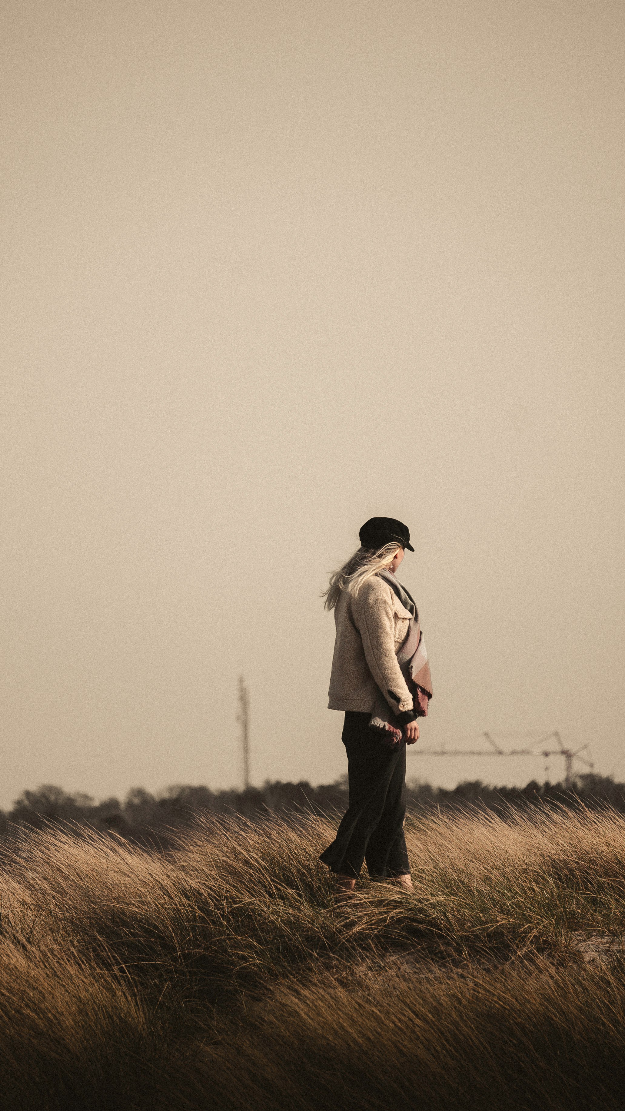 woman in white long sleeve shirt and black pants standing on brown grass field during daytime