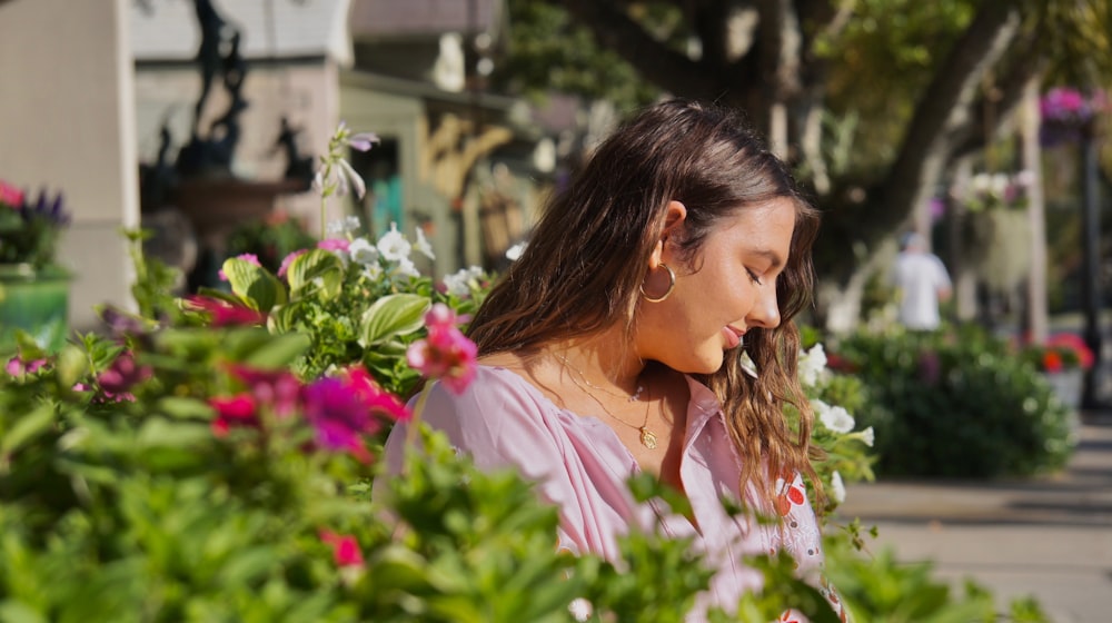 woman in white dress shirt holding pink flowers