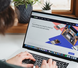 person using macbook pro on white table