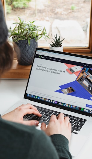 person using macbook pro on white table