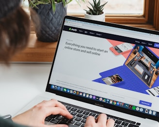 person using macbook pro on white table