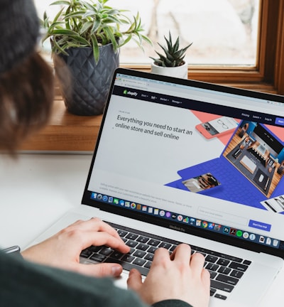 person using macbook pro on white table