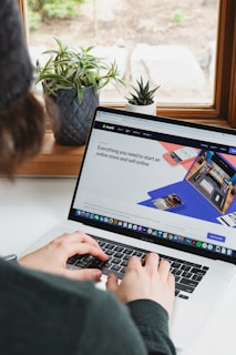 person using macbook pro on white table