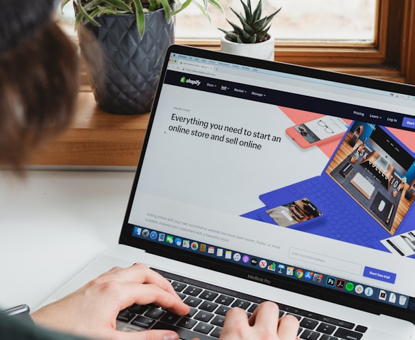 person using macbook pro on white table